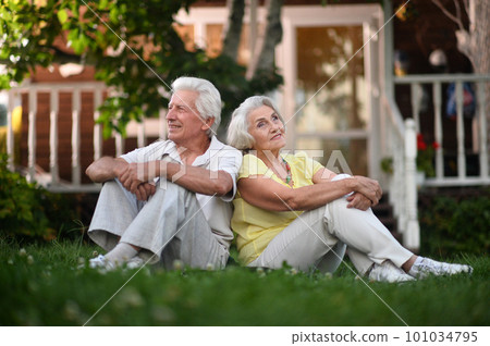Elderly couple sits on the grass in summer Elderly couple sits on the grass in summer 101034795