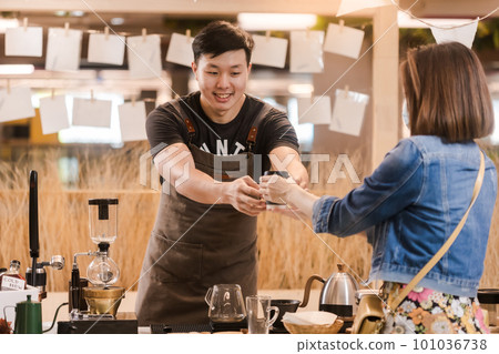 Asian man, coffee maker, handing over a cup of coffee Served to female customers counter, Startup Business Concept. 101036738