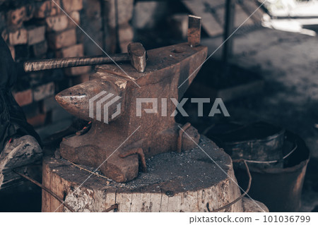 Process metal with hammer on anvil in forge. Strike iron outdoors in workshop with fire. Metalworking, blacksmithing. Process metal with hammer on anvil in forge. Strike iron outdoors in workshop with fire. Metalworking, blacksmithing. 101036799