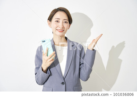 Business woman holding a smartphone and pointing to the right with her palm White background Business woman holding a smartphone and pointing to the right with her palm White background 101036806