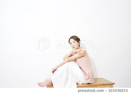 Portrait of a middle-aged woman sitting on a bench, white background, copy space available 101036833