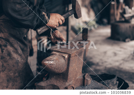 Blacksmith process metal with hammer on anvil in forge. Farrier in dirty clothes strike iron in workshop. Metalworking. 101036839