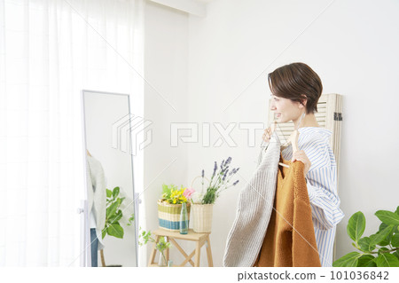 Woman looking at mirror at home and choosing clothes 101036842