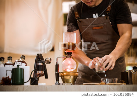 Professional coffee maker - Barista using coffee siphon brewing hot espresso at coffee shop coffee brewing syphon alternative method. Startup Business Concept. Professional coffee maker - Barista using coffee siphon brewing hot espresso at coffee shop coffee brewing syphon alternative method. Startup Business Concept. 101036894