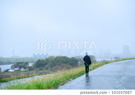 A person walking on the bank on a rainy day A person walking on the bank on a rainy day 101037087