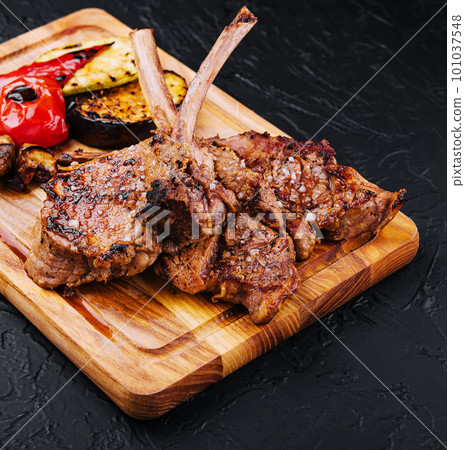 Tasty grilled lamb ribs with vegetables on board 101037548