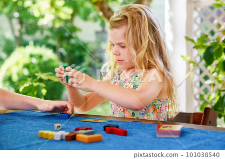 Little preschool girl playing board game with colorful bricks. Happy child build tower of wooden blocks, developing fine motor skills, home joint games. Leisure activities for children at home. Little preschool girl playing board game with colorful bricks. Happy child build tower of wooden blocks, developing fine motor skills, home joint games. Leisure activities for children at home. 101038540