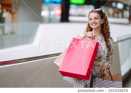 Fashionable woman with multi-colored bags in modern shop center. The joy of consumption. Fashionable woman with multi-colored bags in modern shop center. The joy of consumption. 101038876