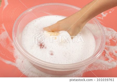 A Basin with Soapy Water, Hand Holds Soapy Sponge with Foam on Pink Background A Basin with Soapy Water, Hand Holds Soapy Sponge with Foam on Pink Background 101039761