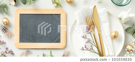 Easter composition, table setting with chalkboard, white plate, golden cutlery, easter eggs and spring branches on light grey background top view flat lay copy space Easter composition, table setting with chalkboard, white plate, golden cutlery, easter eggs and spring branches on light grey background top view flat lay copy space 101039830