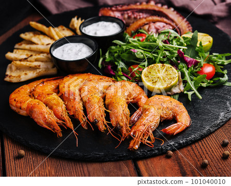 Traditional greek grilled seafood on restaurant wooden plate Traditional greek grilled seafood on restaurant wooden plate 101040010