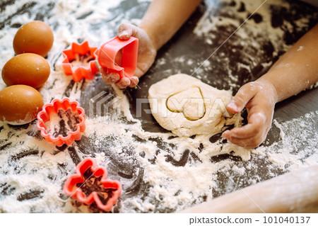 Kids hands cutting out shapes and making cookies. Children's art project, a craft for children. 101040137