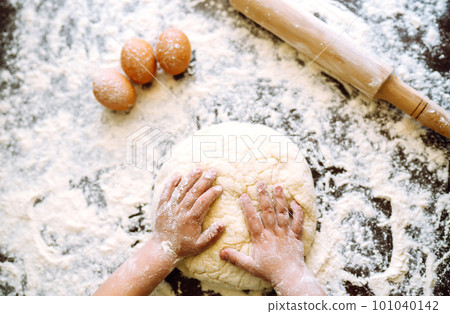 Small hands kneading dough. Little child preparing dough for backing. Kid's hands, some flour. 101040142