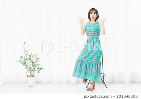 Young woman sitting on a chair and posing surprised Young woman sitting on a chair and posing surprised 101040500