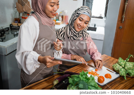 friend with hijab looking at tablet to make new food friend with hijab looking at tablet to make new food 101040668