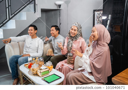Muslim friends laughing together while watching tv Muslim friends laughing together while watching tv 101040671