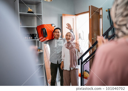 couple carrying suitcases coming back home to family 101040702