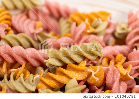 Rice vegetable pasta in the form of spirals in a bowl. Healthy rice pasta with tomatoes, selenera, carrots and beets 101040781
