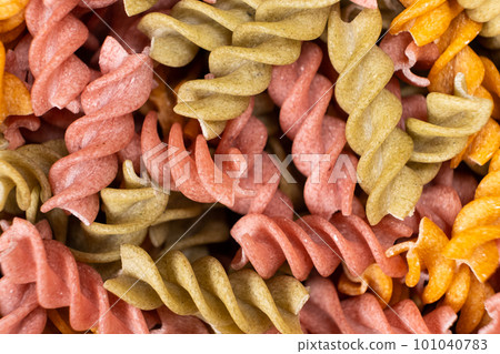 Rice vegetable pasta in the form of spirals, top view. Healthy rice pasta with tomatoes, selenera, carrots and beets 101040783