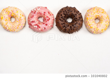Four donuts in a row - white, pink and chocolate on a white background top view Four donuts in a row - white, pink and chocolate on a white background top view 101040802