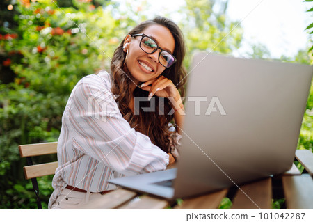 Young woman with wireless headphones calling on laptop, talk by webcam, video conference on cafe. 101042287