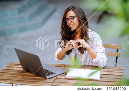 Young woman with wireless headphones calling on laptop, talk by webcam, video conference on cafe. Young woman with wireless headphones calling on laptop, talk by webcam, video conference on cafe. 101042290