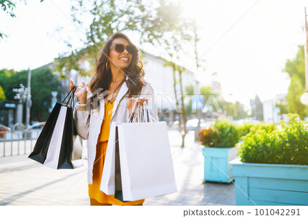 Fashion woman with shopping bags walking on street. Spring Style. Consumerism, shopping, lifestyle. 101042291
