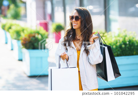 Fashion woman with shopping bags walking on street. Spring Style. Consumerism, shopping, lifestyle. Fashion woman with shopping bags walking on street. Spring Style. Consumerism, shopping, lifestyle. 101042295