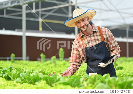 Farmer with digital tablet checking sustainable farming growth or progress in greenhouse. Business agriculture and technology concept Farmer with digital tablet checking sustainable farming growth or progress in greenhouse. Business agriculture and technology concept 101042768