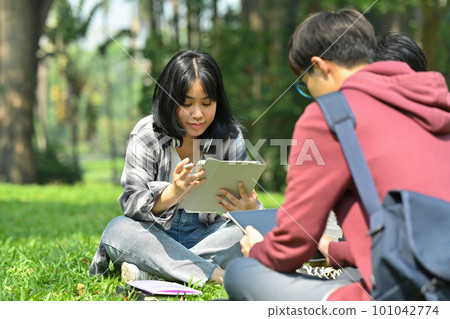 Image of asian female student reading books with her friends at summer park. Education and lifestyle concept 101042774