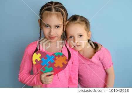 The girl gently laid her head on the shoulder of the older sister holding the autism symbol. 101042918