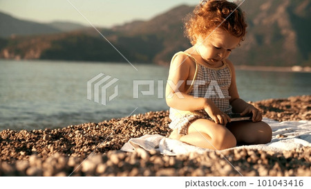 Unhappy little girl uses smartphone on the beach. Travel apps and new user concepts 101043416
