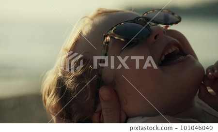 Mother holds smiling little baby girl wearing sunglasses, close-up Mother holds smiling little baby girl wearing sunglasses, close-up 101046040