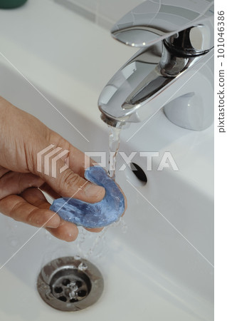 man rinsing his occlusal splint 101046386