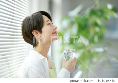 Smiling middle-aged woman holding a glass of water 101046710