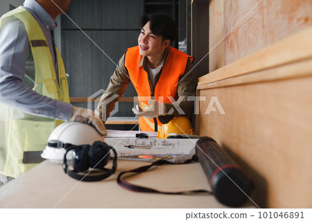 Architect and Engineer working with blueprints for architectural plan, engineer sketching a construction project, green energy concept 101046891