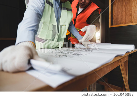 Architect and Engineer working with blueprints for architectural plan, engineer sketching a construction project, green energy concept 101046892