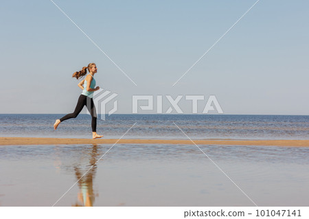 jogging, sporty woman runs in morning on seashore. fitness millennial female trains for marathon jogging, sporty woman runs in morning on seashore. fitness millennial female trains for marathon 101047141