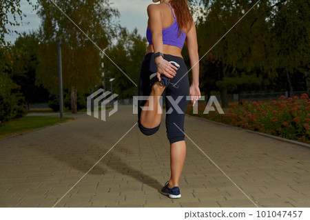 Girl athlete stretching in morning outside, in the city, on a park path surrounded by trees. Active healthy lifestyle. Sport and recreation concept. Girl athlete stretching in morning outside, in the city, on a park path surrounded by trees. Active healthy lifestyle. Sport and recreation concept. 101047457