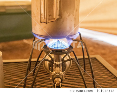 Regulator stove heating the cooker inside a campsite tent 101048348