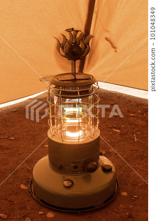 Keeping warm with an oil stove and a stove fan in a tent at a winter campsite 101048349