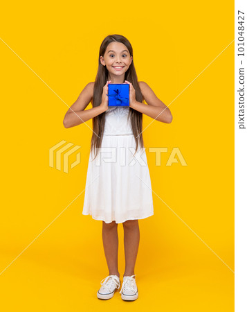 positive teen girl hold present box on yellow background 101048427