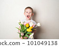 Smiling child with open mouth holding bouquet of flowers 101049138