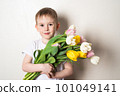 Smiling child with spring flower bouquet looking at camera on a white background 101049141