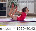 Child performs the exercise gymnastics at home on a mat 101049142