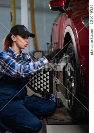 A female auto mechanic makes a camber. Woman working in a car service. A female auto mechanic makes a camber. Woman working in a car service. 101049523