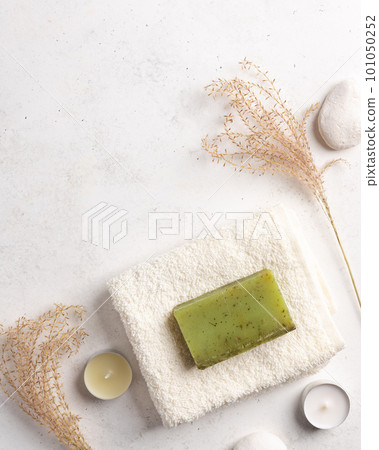 natural soap with herbs and bath towel on a white stone background. natural soap with herbs and bath towel on a white stone background. 101050252