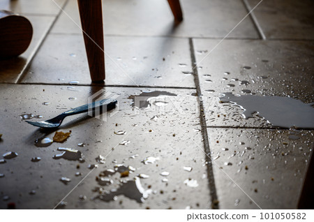 kitchen table with spilled milk, crumbs, and a plastic fork on a brown tile floor kitchen table with spilled milk, crumbs, and a plastic fork on a brown tile floor 101050582
