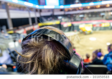 Selective focus on spectators in the stands with hearing protection watching a monster truck rally.  101050583