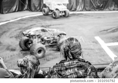 Selective focus on spectators in the stands with hearing protection watching a monster truck rally.  101050792
